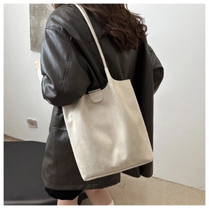 Detail of minimalist beige faux suede bucket bag shown from a stylish side perspective