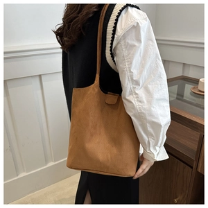 Detail of matte brown bucket bag showing suede texture and minimalist shoulder strap design