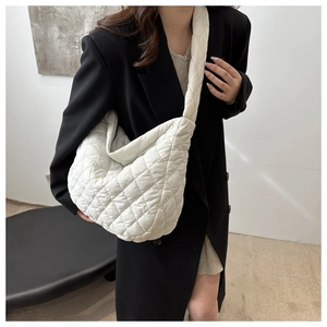 Model wearing a white quilted crossbody bag with rhombic patterns in a modern interior