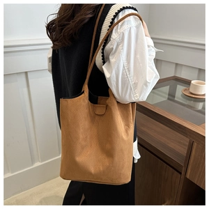 Detailed view of brown matte suede bucket bag worn by model in a minimalist setting
