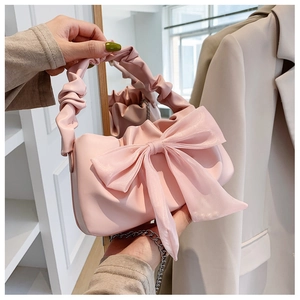 Detailed view of pink handheld bag featuring a large organza bow and ruched handle