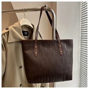 Close-up of deep brown tote bag featuring vertical woven texture and leather straps
