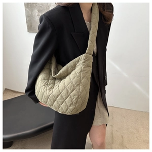 Detail of avocado green quilted hobo bag with padded shoulder strap on model