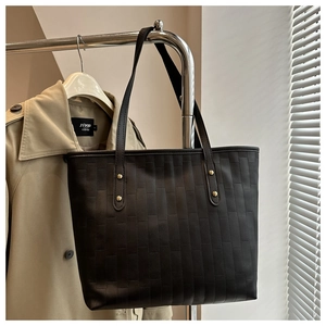 Macro view of black oversized tote bag with rectangular quilted pattern and metal rivets