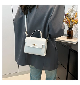 White leather mini crossbody bag with gold twist lock shown on a female model