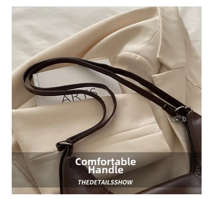 Detail of smooth dark brown matte leather bag with silver zipper on beige blazer