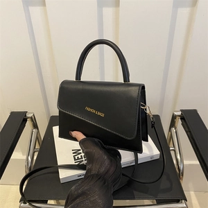 Sac bandoulière minimaliste en cuir noir mat avec rabat asymétrique et lettrage doré