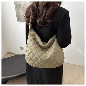 Close-up of a light green quilted crossbody bag showing soft texture and large capacity