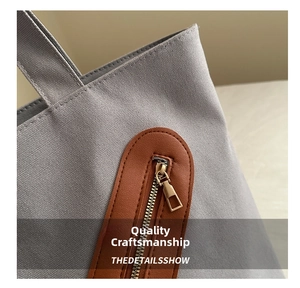 Détail du sac cabas en toile grise avec finitions en cuir marron et fermeture éclair dorée