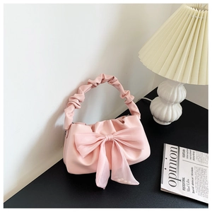 Detailed close-up of a light pink handbag with organza bow and ruffled handle detail