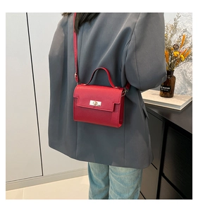 Detailed back view of a red textured leather crossbody square bag on a gray suit