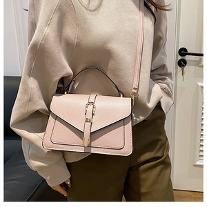 Pink litchi texture small square bag with metal clasp shown in a crossbody style