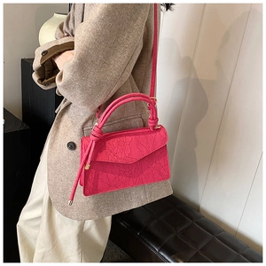 Detail of rose pink handbag with lace texture and round handle on model