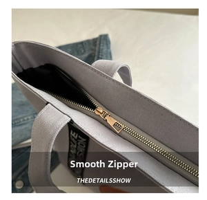 Détail de la fermeture éclair dorée et sangle en toile sur un sac cabas couleur lilas