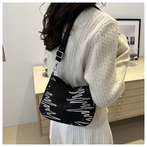Détail d'un sac bandoulière noir avec motifs vagues colorés porté par un mannequin