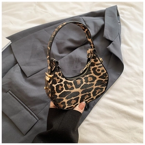 Chic leopard print crescent handbag with gold hardware displayed on grey fabric