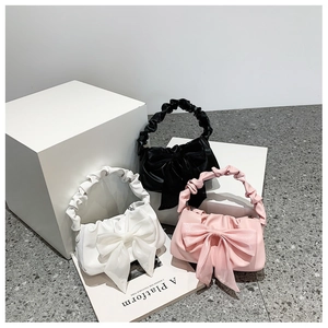 Close-up of bow handbags with pleated handles in black, white, and pink leather