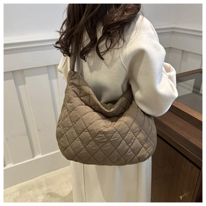 Detail of brown quilted hobo bag with wide strap on shoulder for daily commute