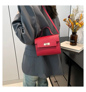 Close-up of a vibrant red textured leather handbag with a gold twist lock and a top handle