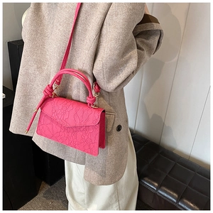 Detail of rose red crossbody bag with embossed floral texture on premium synthetic leather