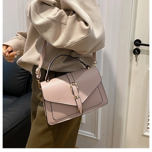 Close-up of pink crossbody bag with cross-grain texture and gold metal buckle detail