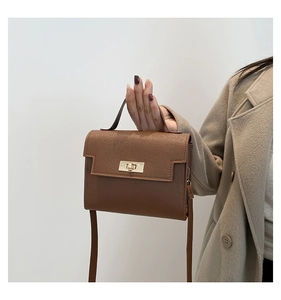 Detail of caramel brown crossbody bag with gold twist lock and saffiano leather texture