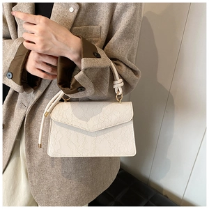 Detail of white lace textured handbag with knotted rope handle and gold metal rings