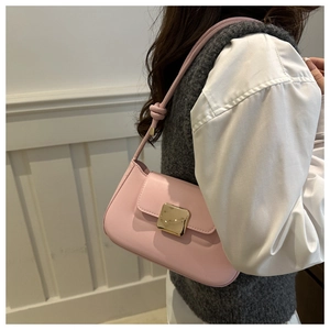 Close-up of pink underarm bag with gold buckle and stylish knotted shoulder strap detail