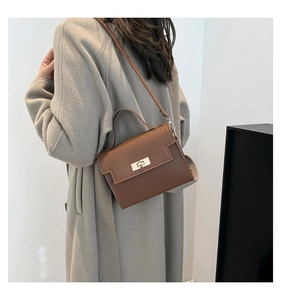Brown leather crossbody bag with golden metal twist lock shown worn by a model