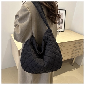 Close-up of black quilted shoulder bag featuring minimalist diamond pattern and wide strap