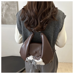 Detailed view of brown faux leather tote with plush decor on a model's back