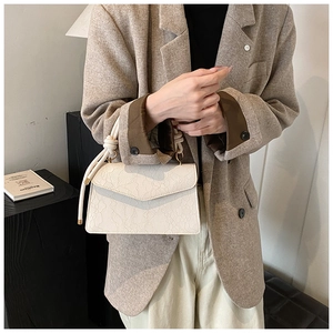 Detail of cream lace texture handbag with unique thick rope knot handle and gold hardware