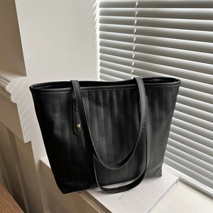 Large black woven tote bag with leather handles and gold rivet accents for daily commuting