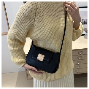 Detail of minimalist black faux leather shoulder bag with square gold metal buckle clasp