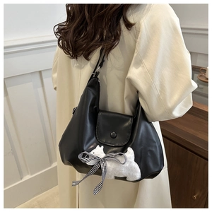 Close-up of black leather tote with cute white puppy patch and checkered bow details