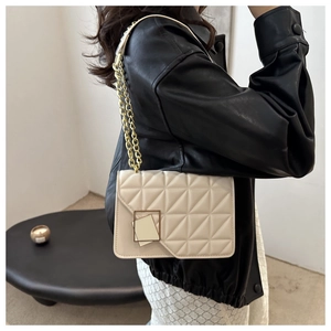 Close-up of beige quilted crossbody bag with gold square clasp and chain strap
