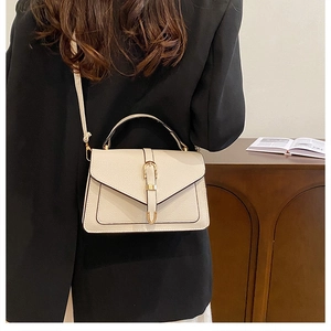 Detail view of cream leather shoulder bag with U-shaped metal buckle and adjustable strap