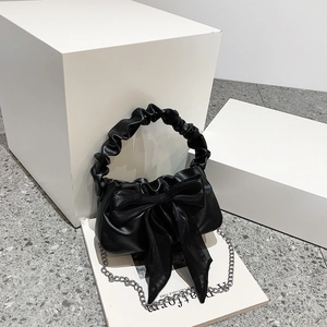 Vintage black handbag with scrunchie handle and mesh bow on geometric white background