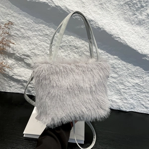 Minimalist light gray faux fur handbag with leather strap on a textured winter background