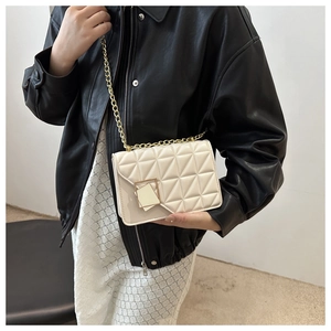 Detail of cream crossbody bag showing geometric quilting and gold chain strap