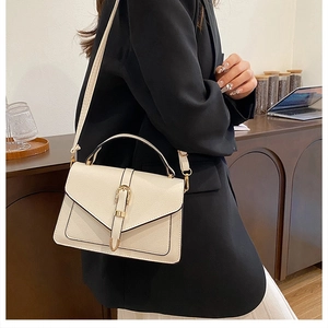 Close-up of cream textured faux leather handbag with gold buckle and top handle