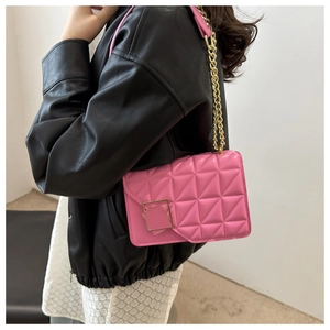 Sac à bandoulière matelassé rose avec chaîne dorée porté sur un blouson en cuir noir