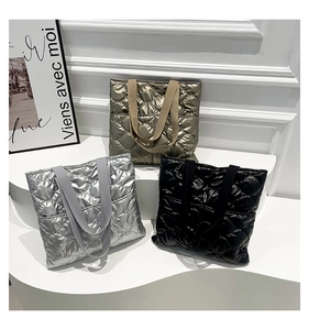 Détails de sacs cabas matelassés en bronze, argent et noir sur des marches blanches