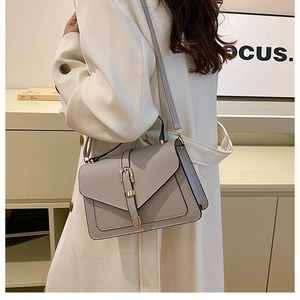 Detail of grey lychee textured crossbody bag with gold metal buckle and envelope flap