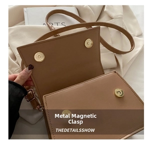 Detail view of the secure golden magnetic snap closure on a brown PU leather handbag