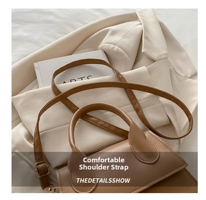 Close-up of golden hardware and adjustable leather strap on a stylish brown crossbody bag