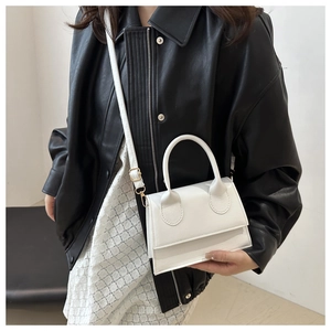 White small PU leather square handbag with gold hardware and adjustable strap on a model