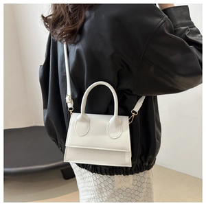 Back view of a model wearing a white trapezoid crossbody bag with black leather jacket
