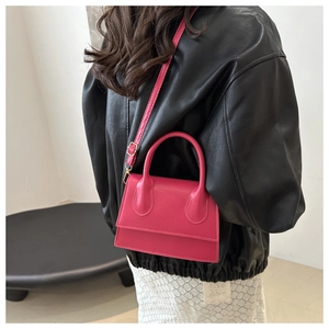Detailed back view of a vibrant magenta leather crossbody bag with a round handle
