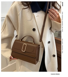 Detailed view of dark brown leather handbag with gold buckle and adjustable strap